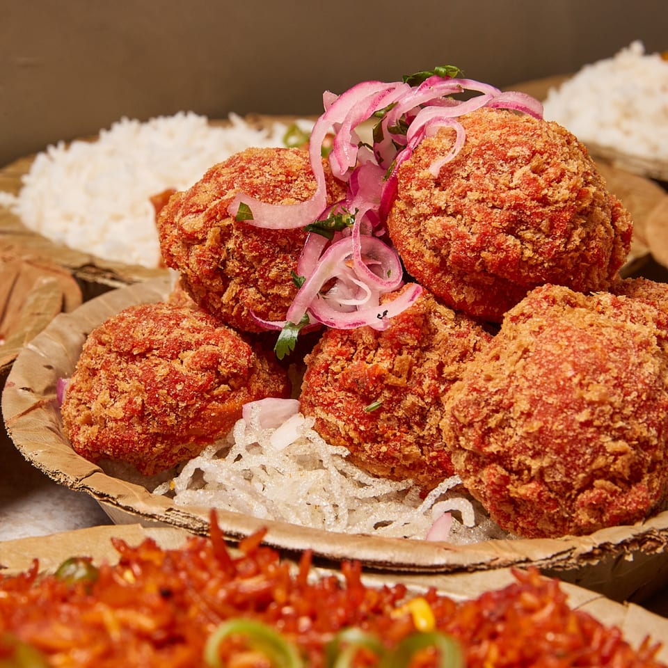 Crispy fried Nepalese momos topped with red onions and cilantro, served with rice and chili.
