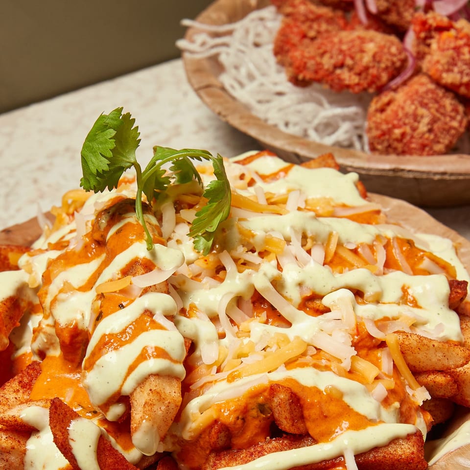 Momo Souls' spicy fries topped with creamy sauces, shredded cheese, and fresh cilantro.