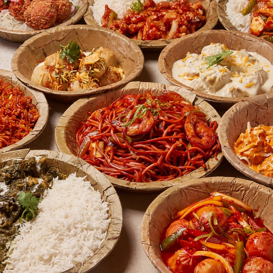 Assortment of Nepalese dishes from Momo Souls, including noodles, momos, rice, and curries in bowls.